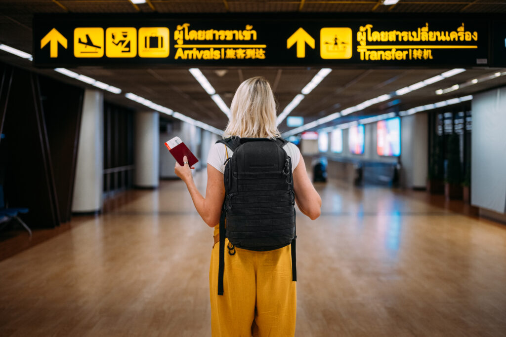 A woman at the airport holding a passport with a boarding pass